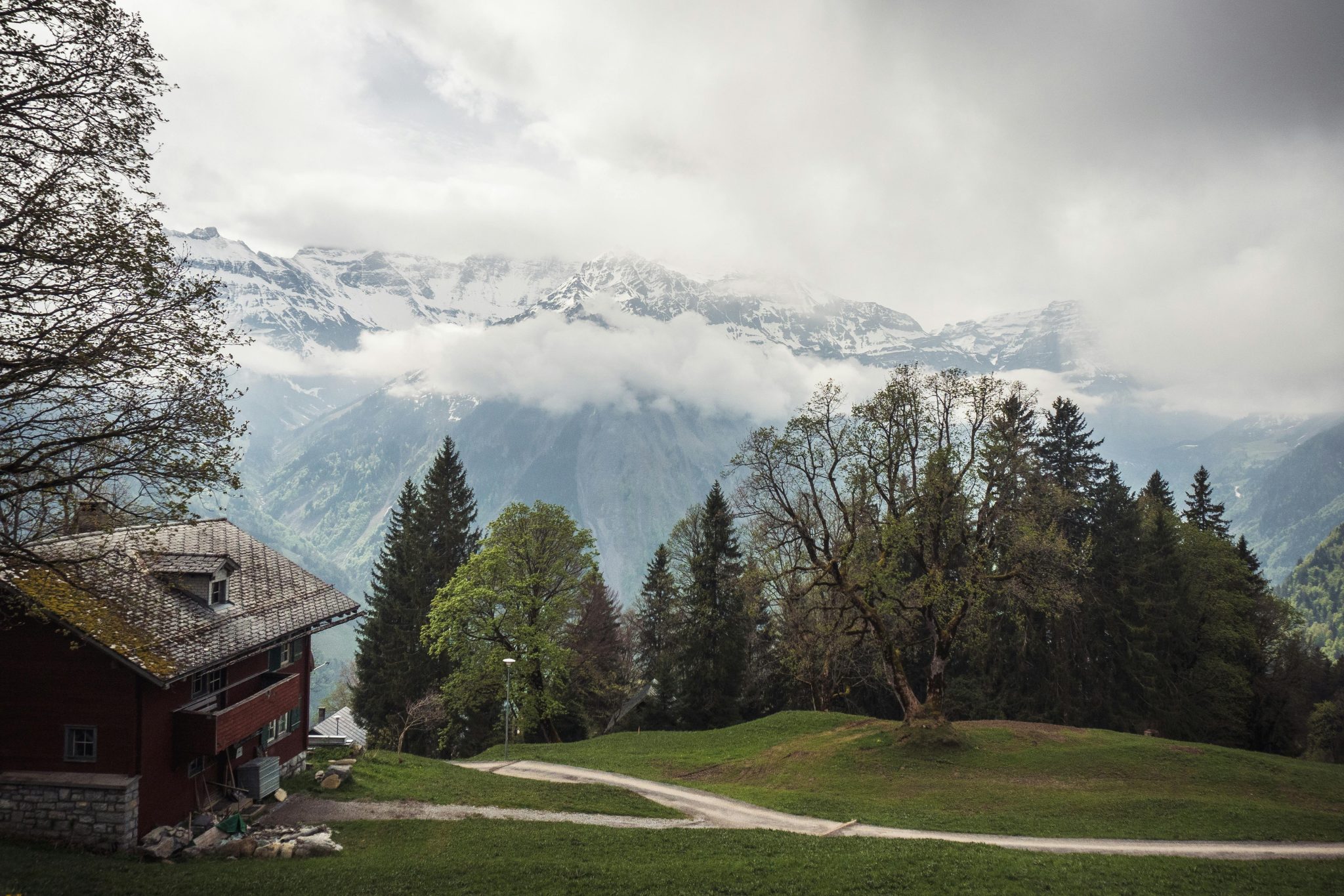 Peaceful mountain scene featuring a rustic house and snow-capped peaks.