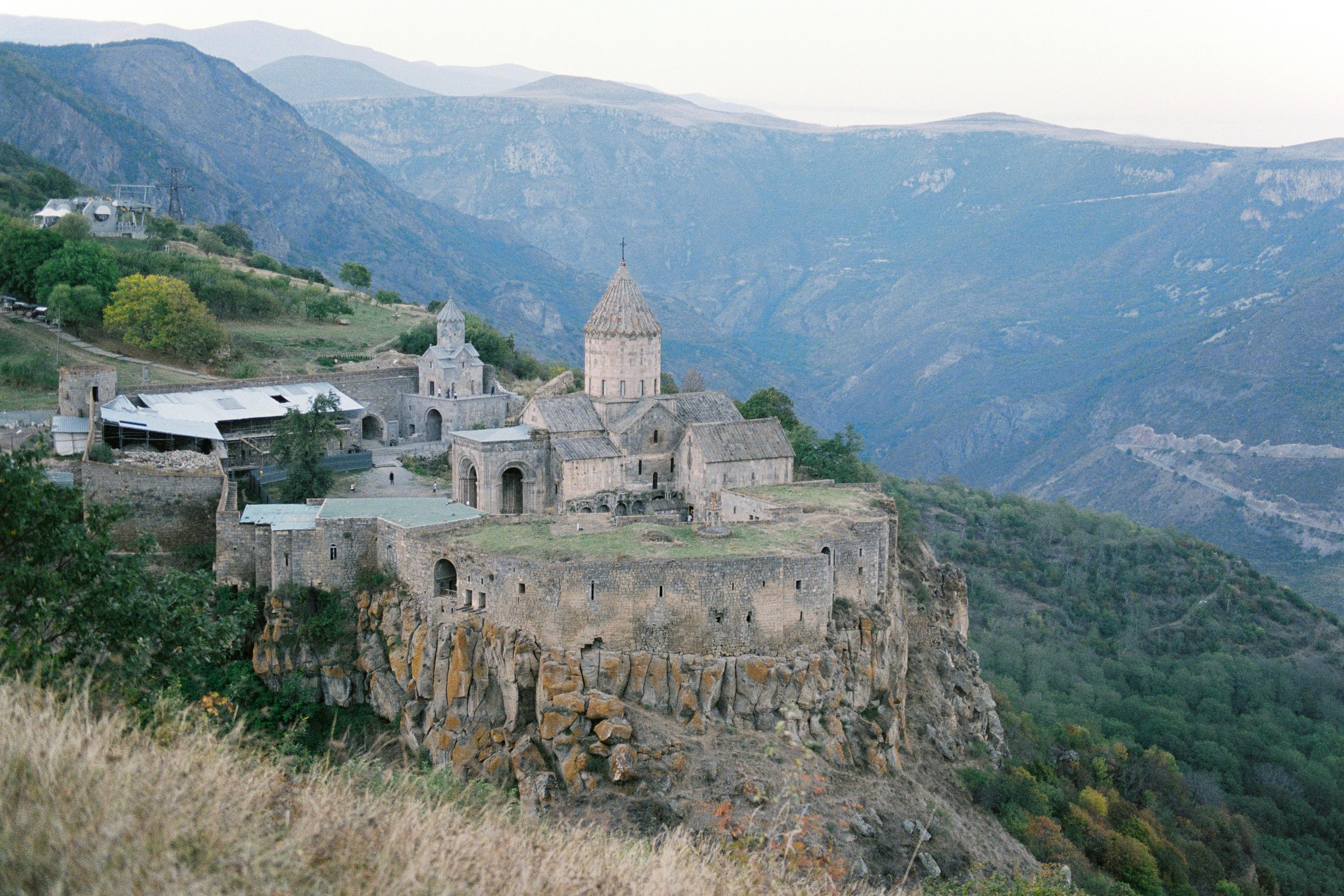 Beautiful view of an ancient monastery perched atop a cliff in a mountainous landscape.