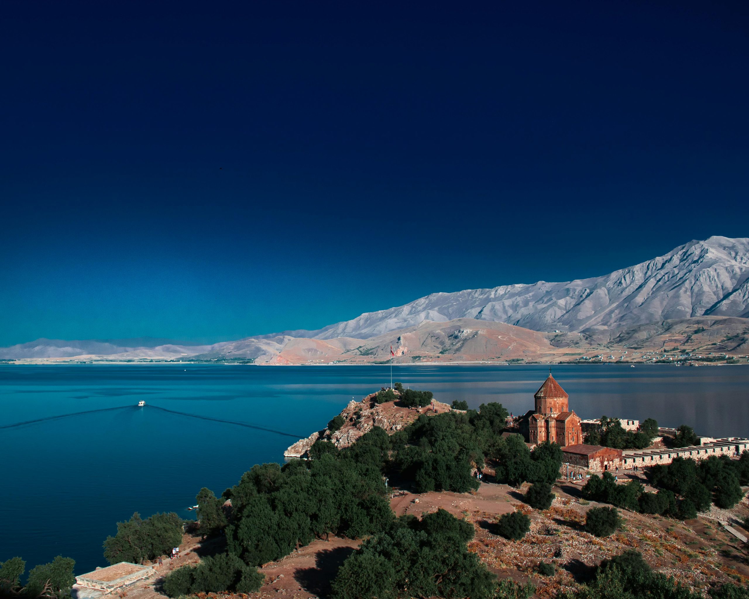Breathtaking aerial shot of Akdamar Church on Lake Van with mountain backdrop.